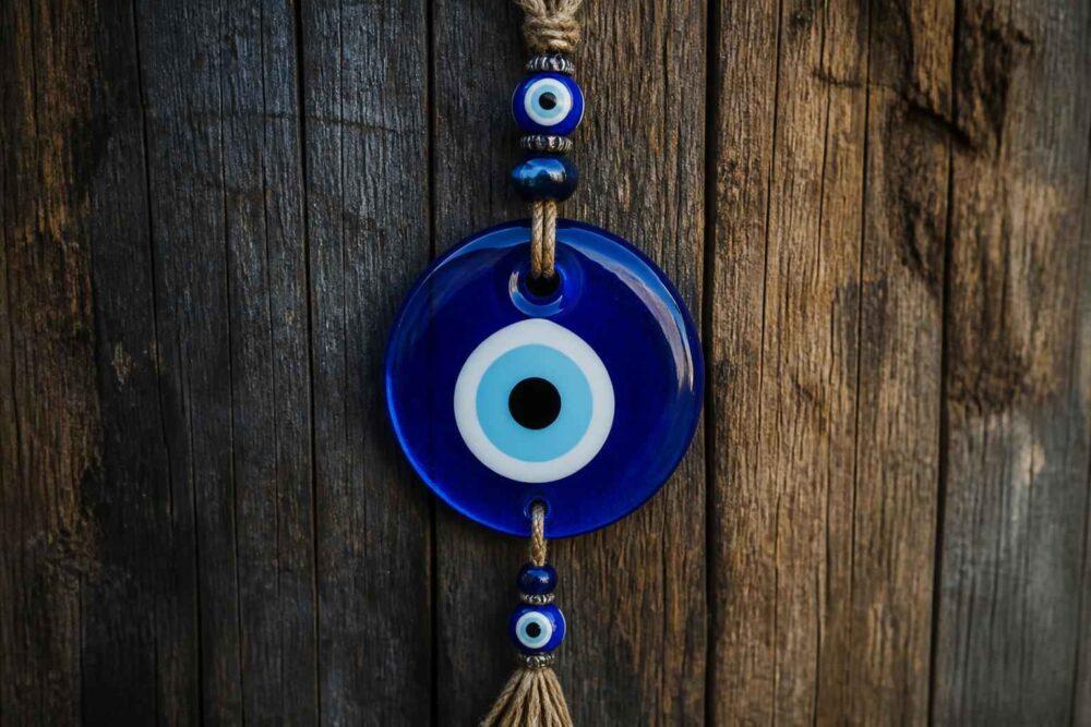 Niebieski amulet w kształcie oka zawieszony na ciemnej drewnianej desce